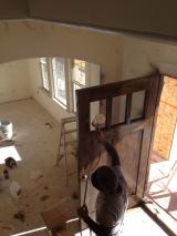 Front door being painted with sprayer by workman
