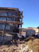 Workman working on stuco on back right of house
